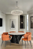 Black and white marble top round modern dining table with 8 orange curved faux leather dining chairs in orange and black